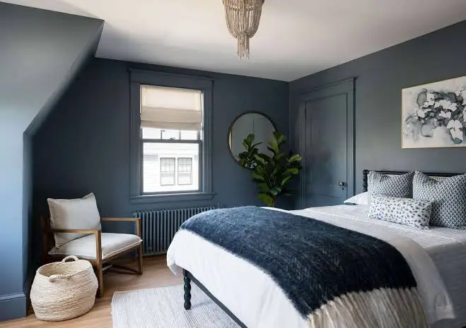 Bedroom with dark blue painted walls and matching trim by an interior painter in Dennis, MA.