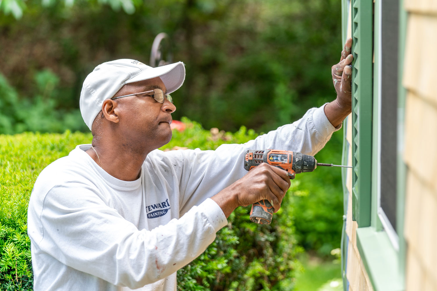 Man replacing shutters on exterior window