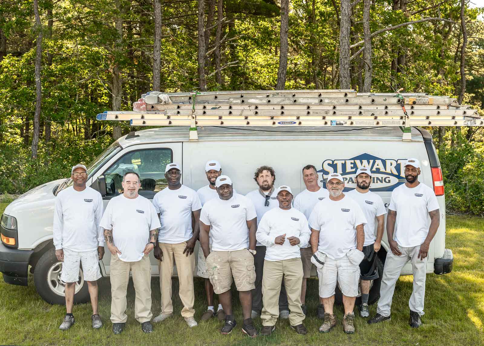 Eleven crew leaders standing in front of the Stewart Painting work van.