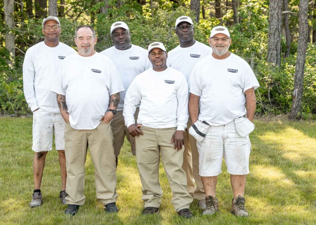 Six crew leaders of the painting division standing in front of trees.