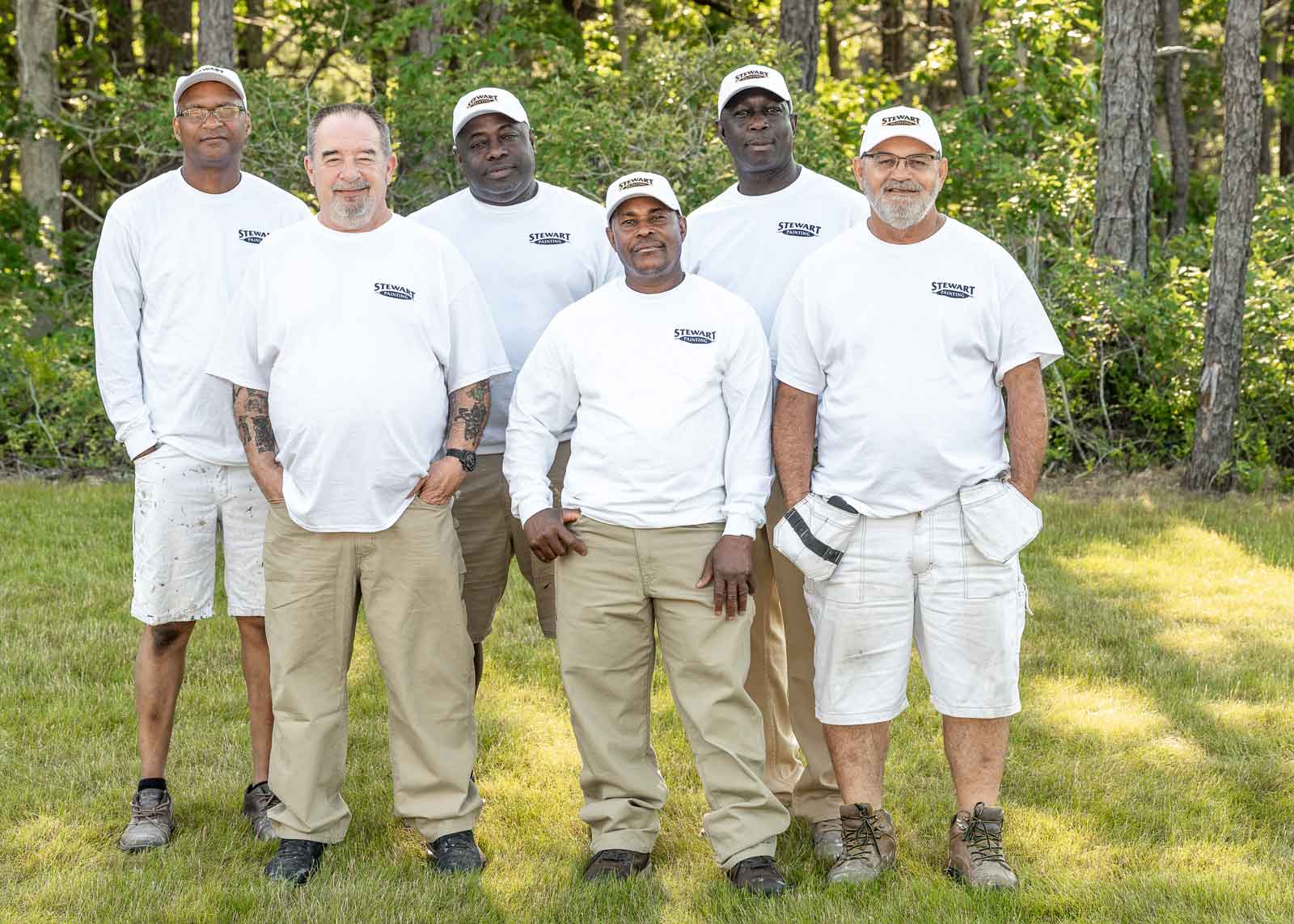 Six crew leaders of the painting division standing in front of trees.
